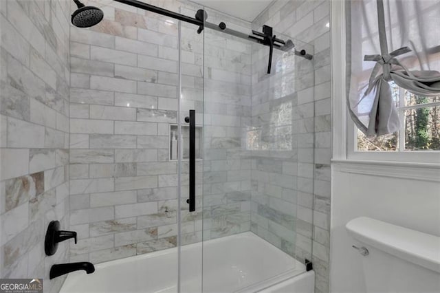 bathroom featuring combined bath / shower with glass door and toilet