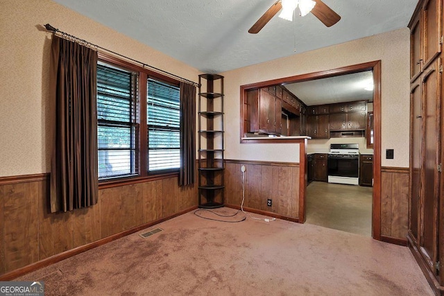 interior space with wood walls, ceiling fan, and a textured ceiling