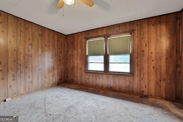 carpeted spare room with wooden walls and ceiling fan