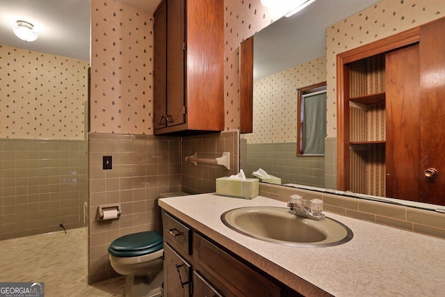 bathroom featuring vanity, tile walls, and toilet