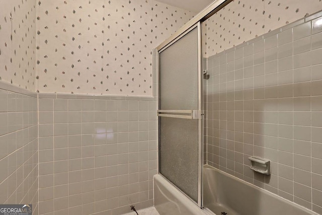 bathroom featuring tile walls and enclosed tub / shower combo