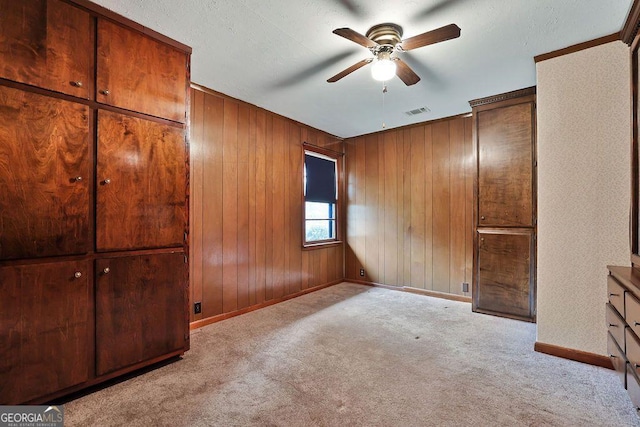 unfurnished bedroom featuring ceiling fan, light carpet, and wooden walls