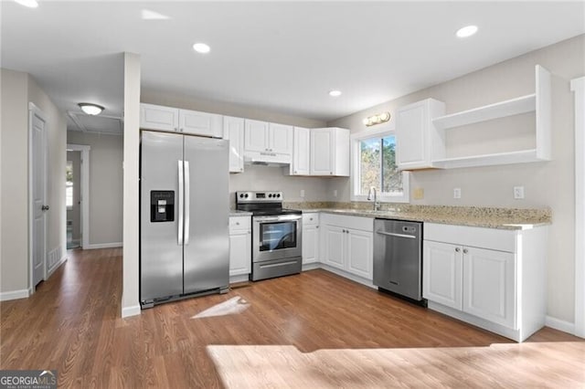 kitchen featuring light stone countertops, appliances with stainless steel finishes, sink, hardwood / wood-style flooring, and white cabinets