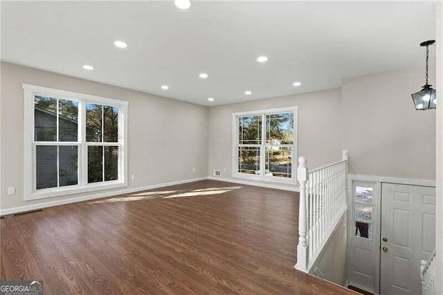 unfurnished living room with dark hardwood / wood-style flooring and plenty of natural light