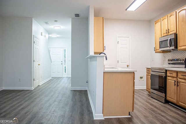 kitchen with appliances with stainless steel finishes, dark hardwood / wood-style flooring, light brown cabinetry, and backsplash