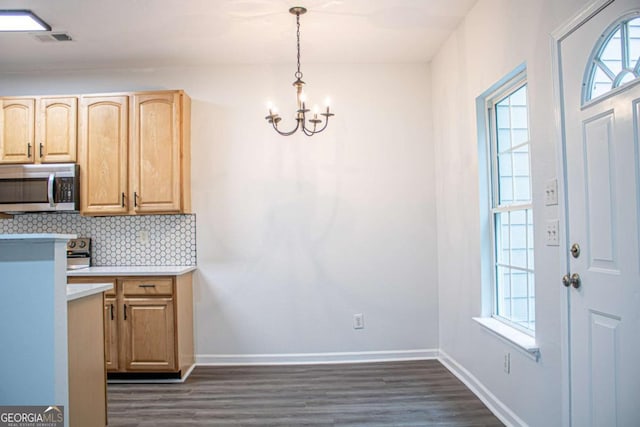 kitchen with a healthy amount of sunlight, light brown cabinets, pendant lighting, and an inviting chandelier