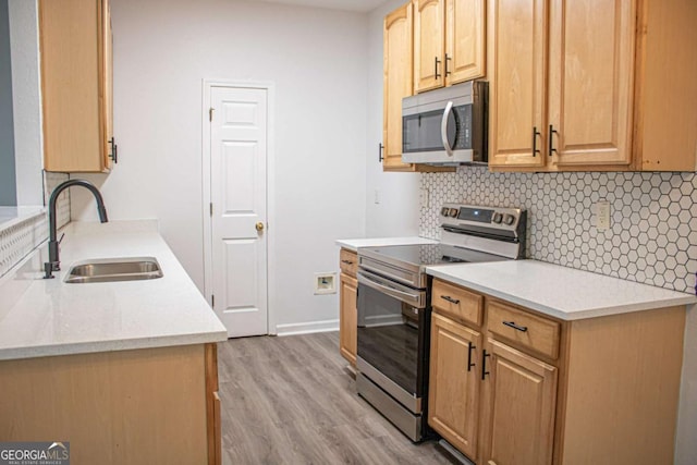 kitchen with decorative backsplash, appliances with stainless steel finishes, light hardwood / wood-style flooring, and sink