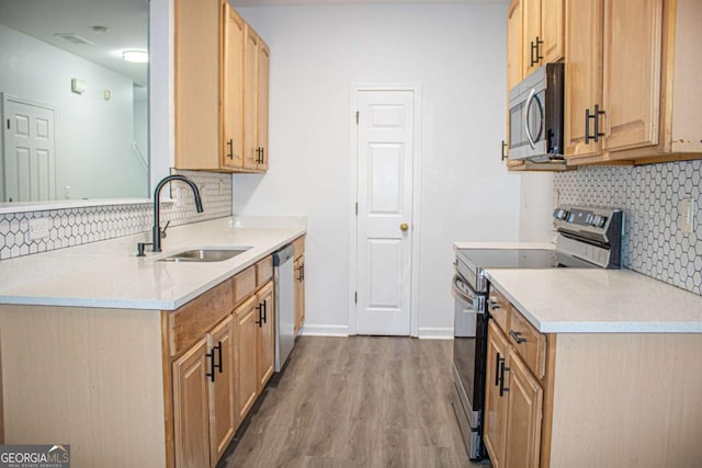 kitchen with backsplash, stainless steel appliances, sink, light brown cabinets, and hardwood / wood-style floors