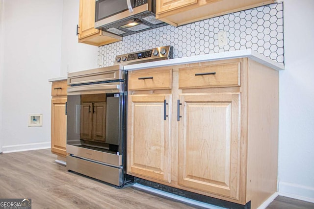 kitchen with appliances with stainless steel finishes, light wood-type flooring, tasteful backsplash, and light brown cabinets