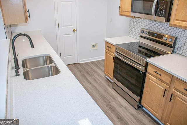 kitchen featuring wood-type flooring, sink, appliances with stainless steel finishes, and tasteful backsplash