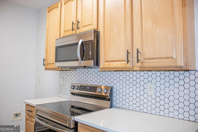 kitchen with light brown cabinetry, backsplash, stainless steel appliances, and light stone counters