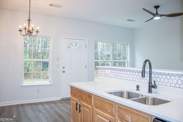 kitchen featuring sink, dark wood-type flooring, backsplash, pendant lighting, and ceiling fan with notable chandelier