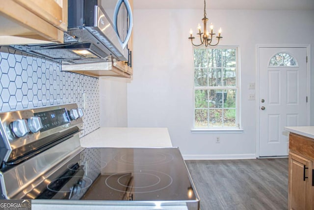 kitchen featuring stainless steel range with electric stovetop, backsplash, hanging light fixtures, a notable chandelier, and dark hardwood / wood-style flooring