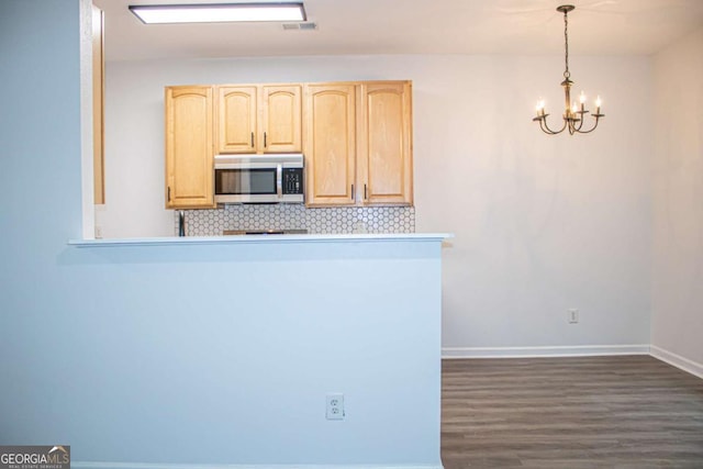 kitchen featuring backsplash, hanging light fixtures, light brown cabinetry, a notable chandelier, and dark hardwood / wood-style flooring