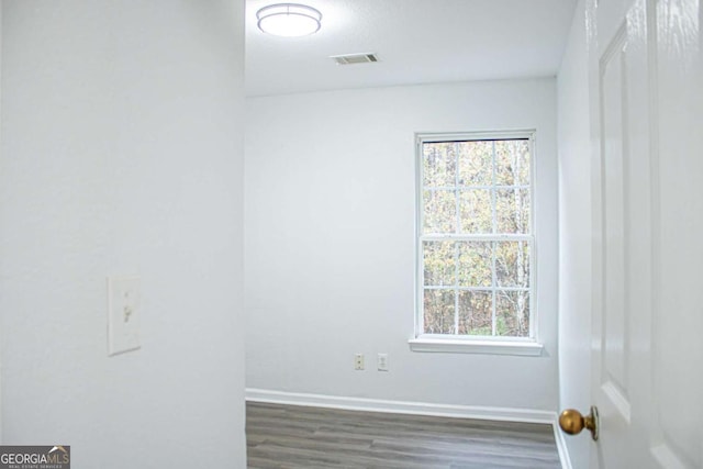 empty room with dark hardwood / wood-style flooring and a healthy amount of sunlight