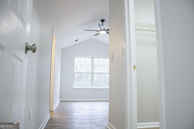 corridor with hardwood / wood-style floors and lofted ceiling