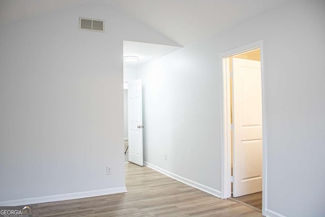 corridor with light hardwood / wood-style flooring and lofted ceiling