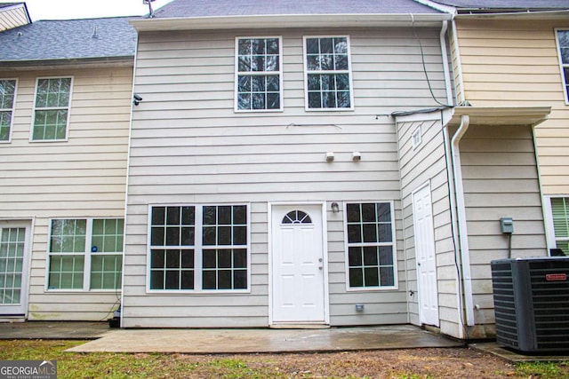 back of property with central AC and a patio