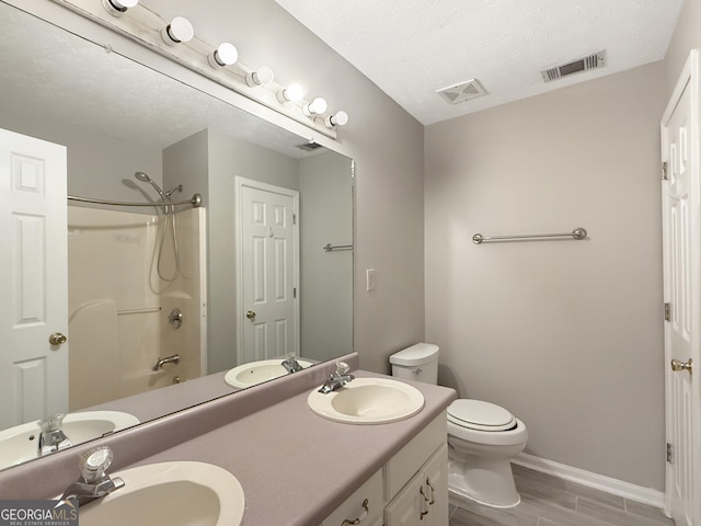 full bathroom featuring vanity, a textured ceiling, bathing tub / shower combination, hardwood / wood-style flooring, and toilet