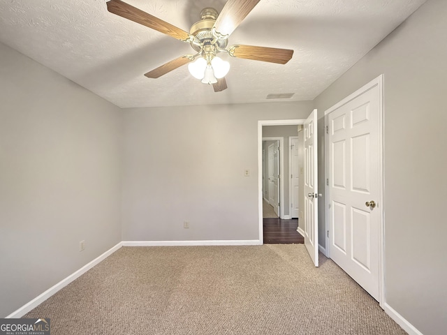 unfurnished bedroom with carpet flooring, a textured ceiling, and ceiling fan