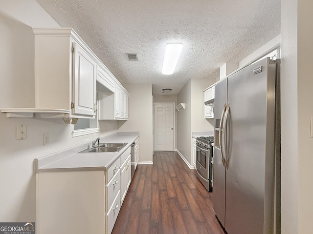 kitchen featuring appliances with stainless steel finishes, dark hardwood / wood-style flooring, a textured ceiling, sink, and white cabinets