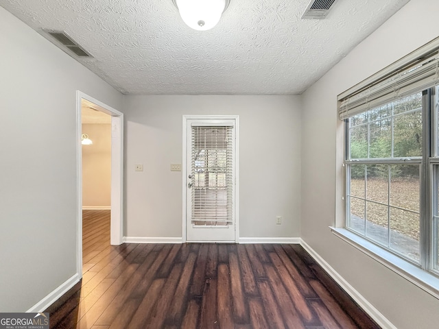 unfurnished room with dark hardwood / wood-style flooring and a textured ceiling