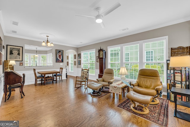 living room with ceiling fan with notable chandelier, light hardwood / wood-style floors, and crown molding