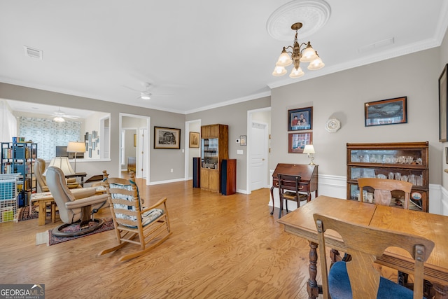 living room with ceiling fan with notable chandelier, light hardwood / wood-style flooring, and crown molding