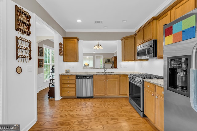 kitchen with sink, light stone counters, light hardwood / wood-style flooring, a notable chandelier, and appliances with stainless steel finishes