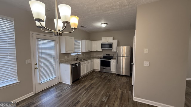 kitchen featuring white cabinetry, hanging light fixtures, stainless steel appliances, an inviting chandelier, and dark hardwood / wood-style flooring