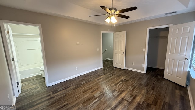 unfurnished bedroom with ensuite bathroom, ceiling fan, dark hardwood / wood-style flooring, and a closet