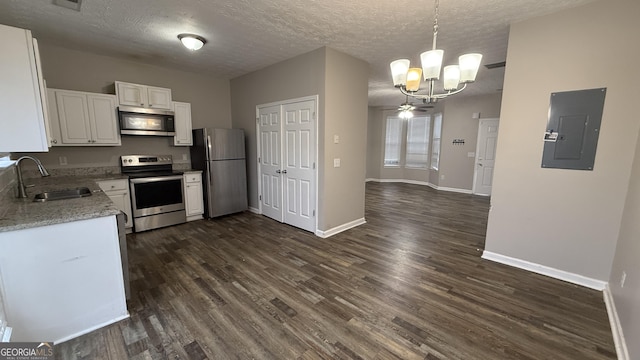 kitchen featuring dark wood-type flooring, sink, appliances with stainless steel finishes, decorative light fixtures, and white cabinetry