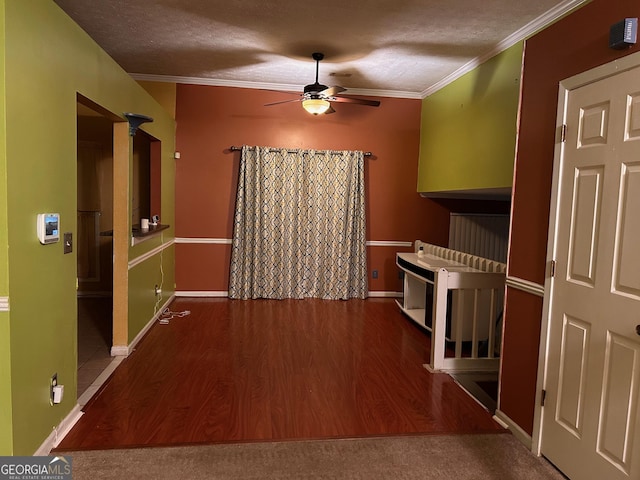 unfurnished dining area featuring ceiling fan, crown molding, a textured ceiling, and wood finished floors