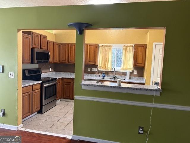 kitchen featuring sink, light tile patterned floors, a textured ceiling, ornamental molding, and stainless steel refrigerator