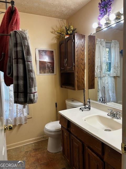 bathroom with vanity, a textured ceiling, and toilet