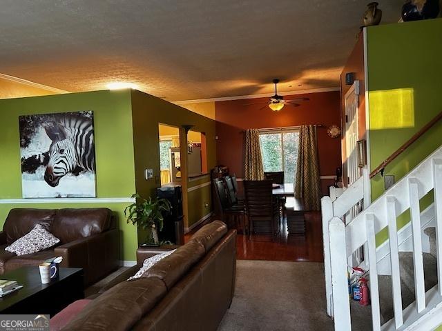 carpeted living area featuring stairs and ceiling fan