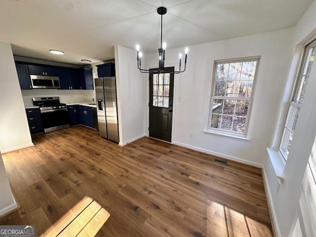 unfurnished dining area with a chandelier, a textured ceiling, and dark hardwood / wood-style flooring