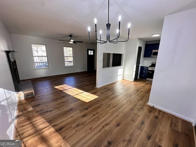 unfurnished dining area featuring a textured ceiling, dark wood-type flooring, and ceiling fan with notable chandelier