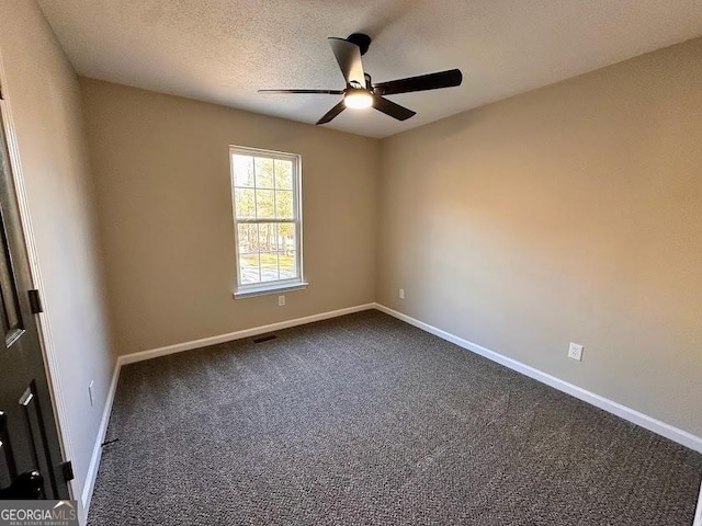 empty room with ceiling fan, a textured ceiling, and dark colored carpet