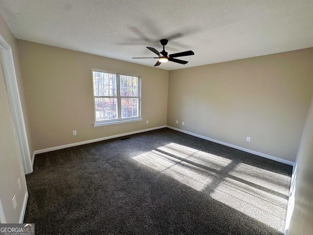 empty room with ceiling fan, dark carpet, and a textured ceiling