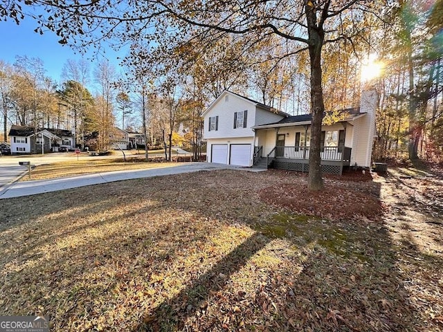 view of property exterior with a porch, a garage, and a lawn