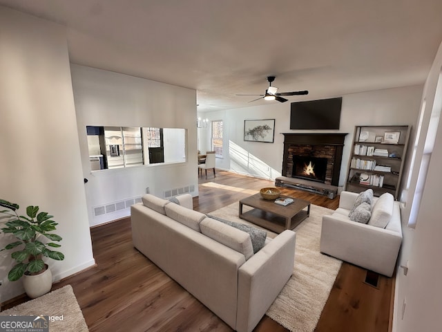 living room featuring a fireplace, ceiling fan with notable chandelier, and hardwood / wood-style flooring