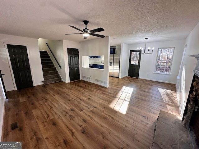 unfurnished living room featuring dark hardwood / wood-style flooring, ceiling fan with notable chandelier, and a textured ceiling