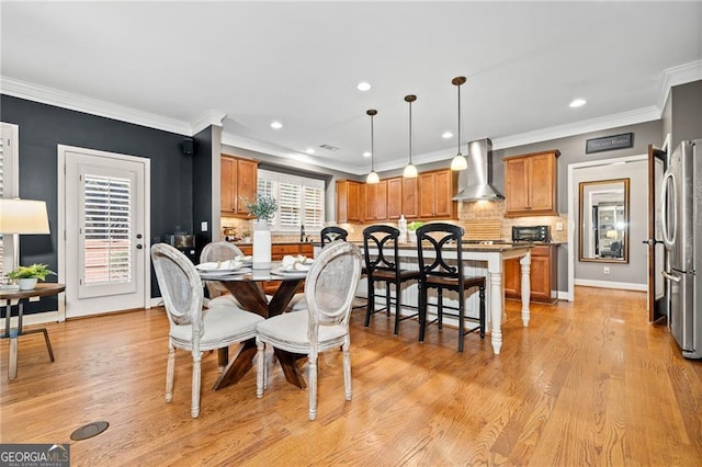 dining area featuring light wood-type flooring and crown molding