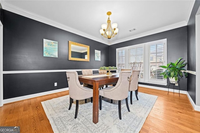 dining room featuring a chandelier, crown molding, and light hardwood / wood-style flooring