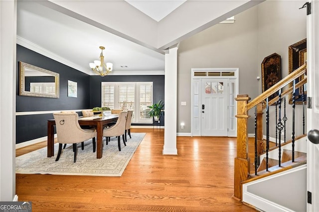 dining area featuring hardwood / wood-style flooring, an inviting chandelier, decorative columns, and ornamental molding