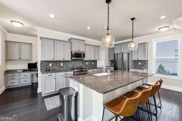 kitchen featuring a kitchen breakfast bar, dark hardwood / wood-style flooring, stainless steel appliances, a kitchen island with sink, and sink