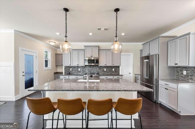 kitchen featuring gray cabinetry, hanging light fixtures, stainless steel appliances, dark hardwood / wood-style floors, and an island with sink