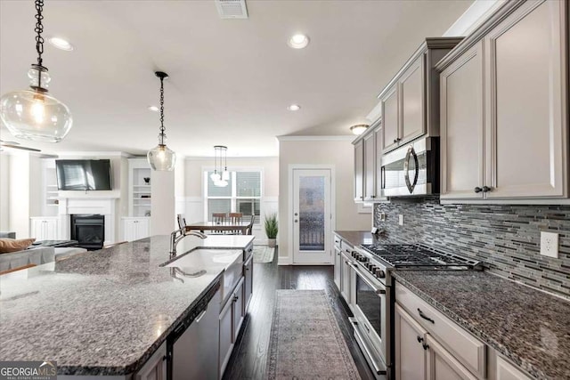 kitchen featuring sink, hanging light fixtures, dark hardwood / wood-style flooring, dark stone countertops, and appliances with stainless steel finishes