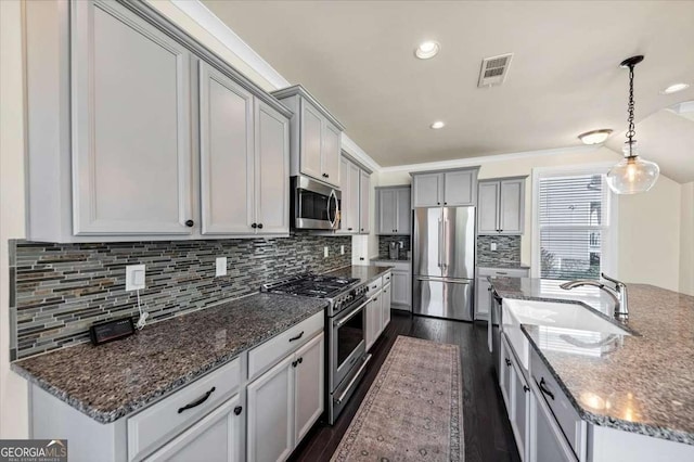 kitchen featuring appliances with stainless steel finishes, dark hardwood / wood-style flooring, gray cabinetry, and pendant lighting